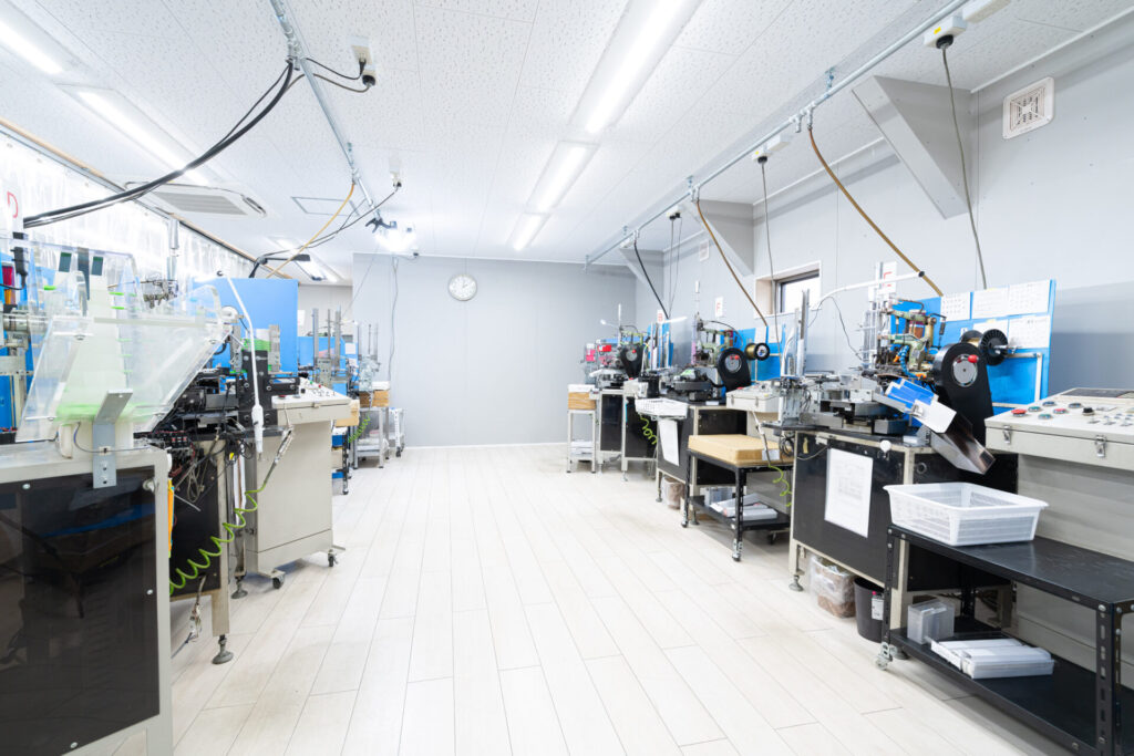 八尾市の歯ブラシメーカー多葉刷子工業所の工場内。植毛機・毛切機・包装機が左右に並ぶ製造ライン。FactorISM 2026の工場見学で公開